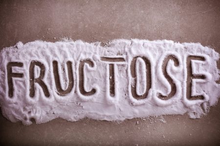Fructose word written in fructose powder over grey background