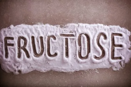 Fructose word written in fructose powder over grey background